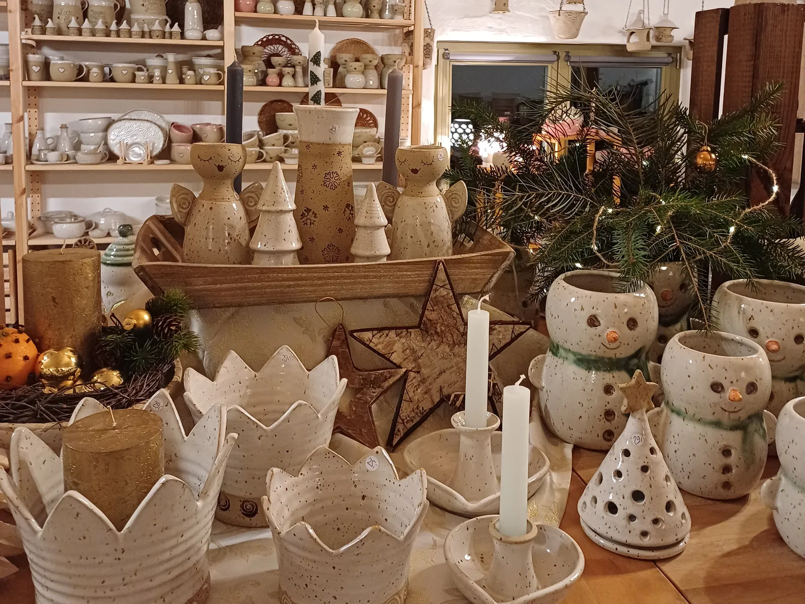 Weihnachtlich geschmückter Verkaufsraum mit Kronen-Windlichtern, Kerzen, Tannengrün und Schneemann-Töpfen